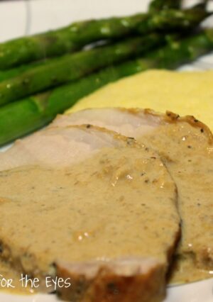 A plate of milk braised pork with gravy and polenta.