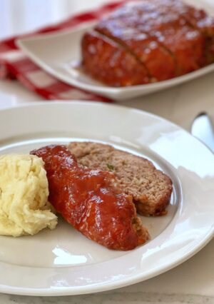 a plate of glazed meatloaf and mashed potatoes