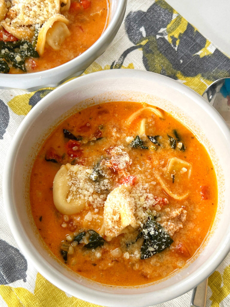 You won't believe how easy this delicious Sausage and Cheese Tortellini Soup recipe is to make! The soup is in a creamy tomato broth, with sausage and spinach. It's so hearty and comforting, too!