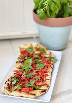 Fresh Tomato Bruschetta, grilled on homemade pizza dough, is a perfect way to enjoy summer tomatoes and basil. This homemade pizza dough can be made in advance. This is even better than pizza delivery, for a lot less money.