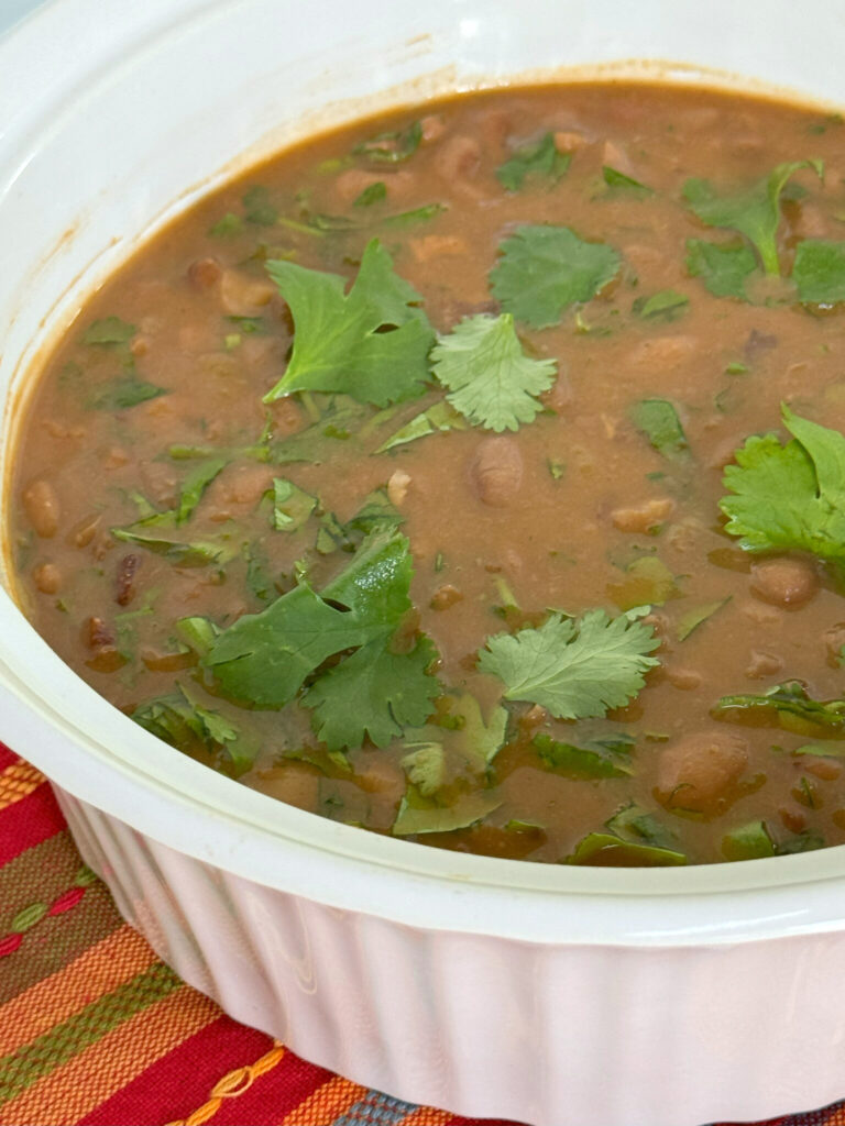 A bowl of beans, garnished with fresh cilantro
