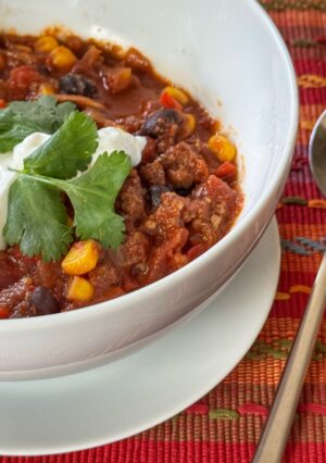 A bowl of black bean chili, garnished with sour cream and cilantro.