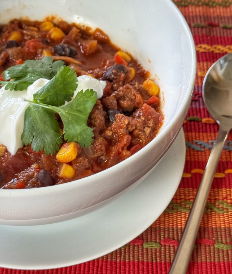 A bowl of black bean chili, garnished with sour cream and cilantro.