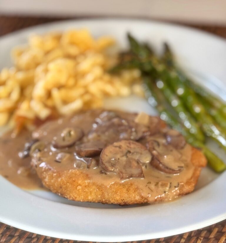 A plate of breaded cutlet with a mushroom cream sauce.